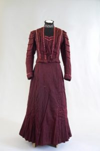 Kostümkleid. Ende 19. Jh. Rot-schwarz melierte Wolle, Tüll, Seide.