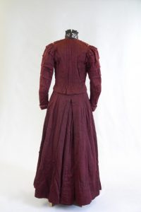 Kostümkleid. Ende 19. Jh. Rot-schwarz melierte Wolle, Tüll, Seide.