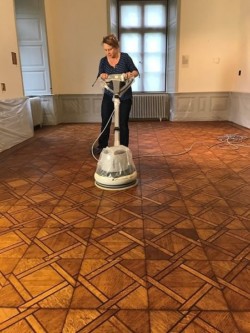 Der Boden wird mit einer Bohnermaschine auf Hochglanz gebracht.